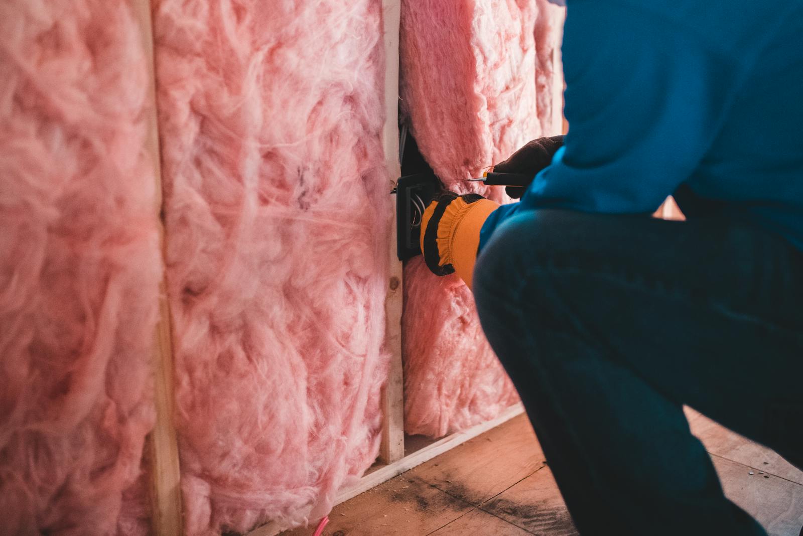 Worker installing stone wool insulation in wall framing