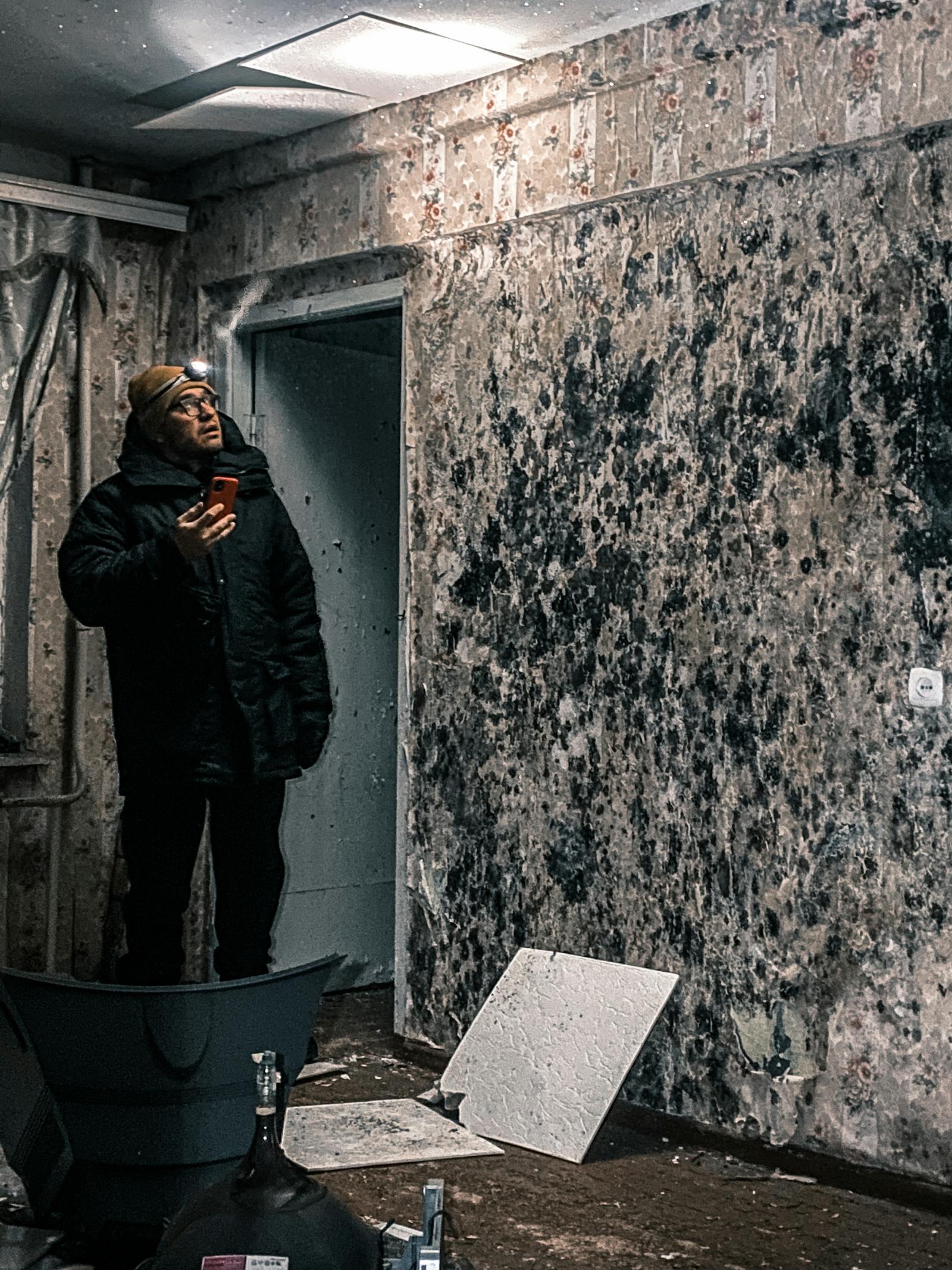 Inspector examining mold-affected walls during a building forensics investigation