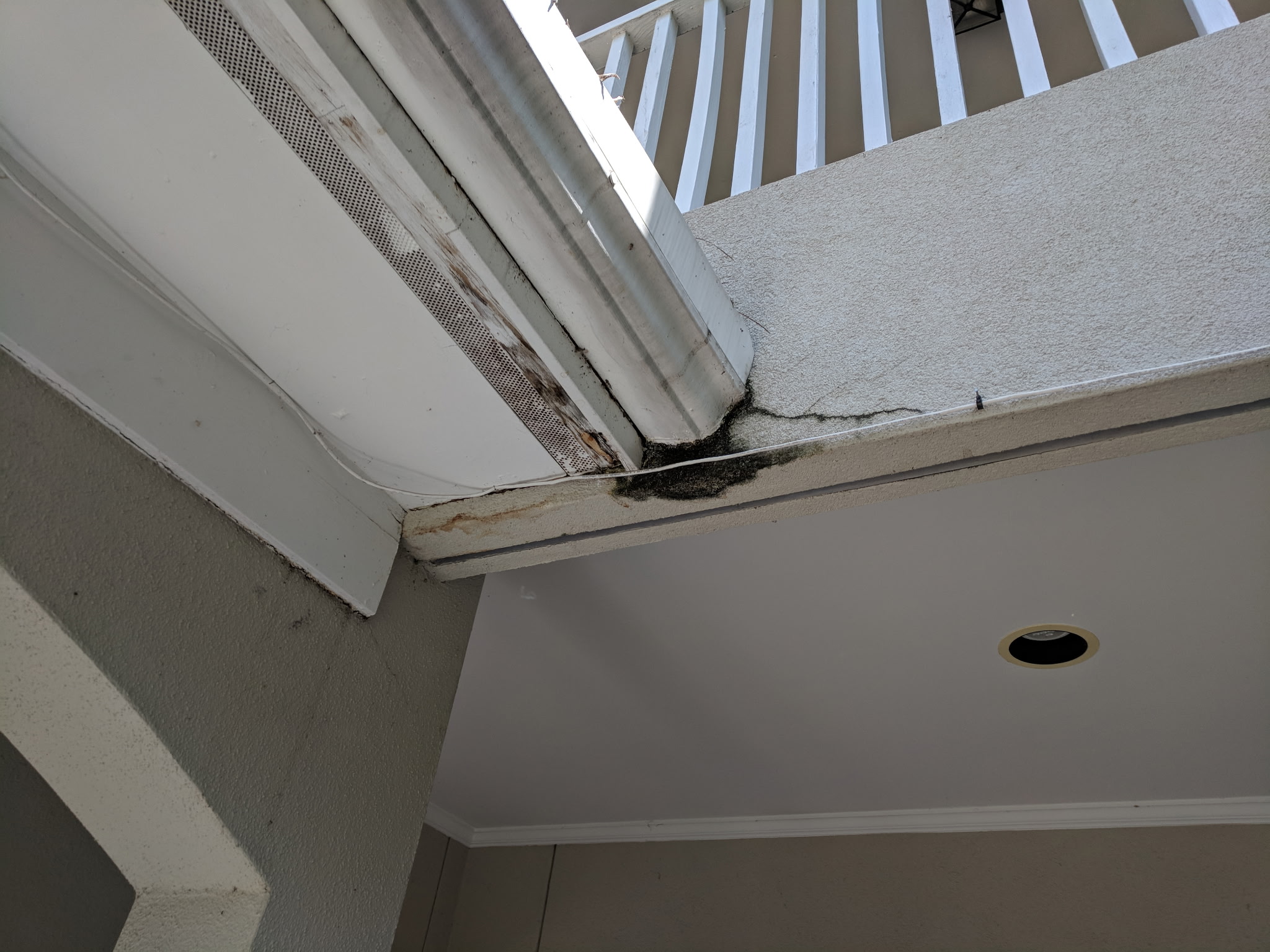 Mold and water damage at a balcony-to-ceiling junction caused by water intrusion